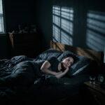 A realistic photo having sleep paralysis explained: a woman waking up in a dark room unable to move.