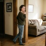 A person pausing thoughtfully at an interior doorway trying to recall a forgotten intention