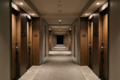 Symmetrical architectural view of a silent empty modern hotel corridor at night with soft warm ceiling lighting