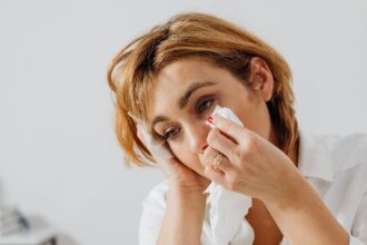 Woman holding back tears with a tissue while experiencing a lump in her throat before crying