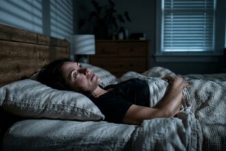 An adult lying awake at night gazing thoughtfully toward the ceiling in quiet nighttime contemplation