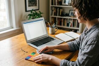 A person organizing and cleaning a desk beside an untouched laptop document illustrating productive procrastination